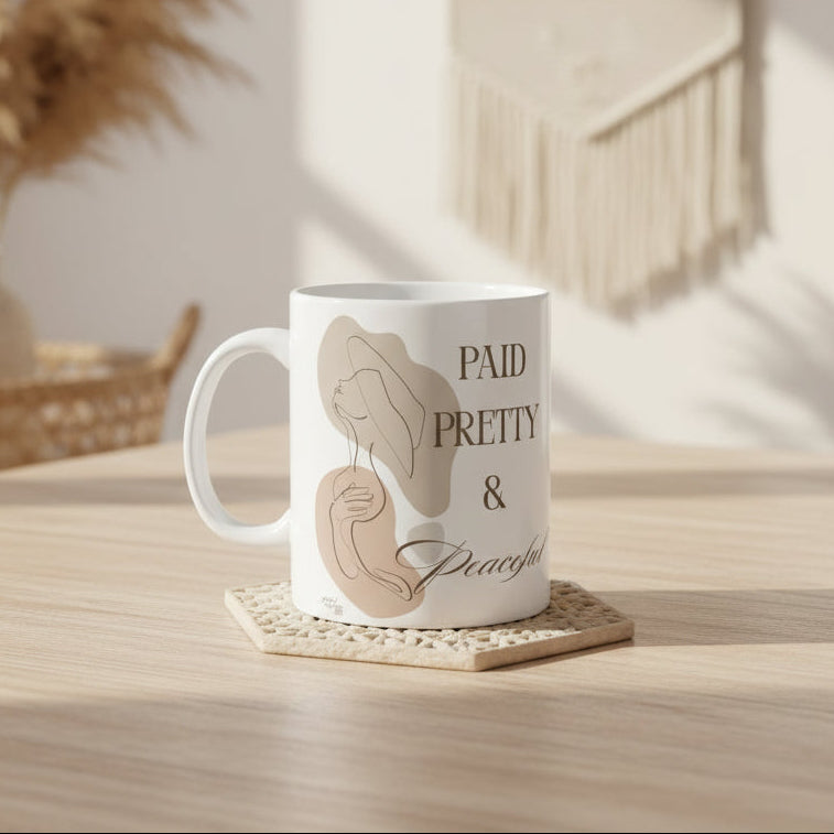White mug with abstract designs and text 'PAID PRETTY & PEACEFUL' on a white background
